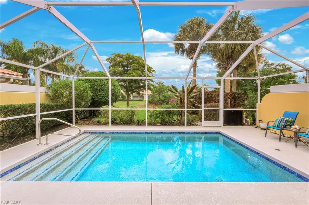 Screened swimming pool enclosure featuring a rectangular pool with tiled steps and a handrail, surrounded by a concrete patio