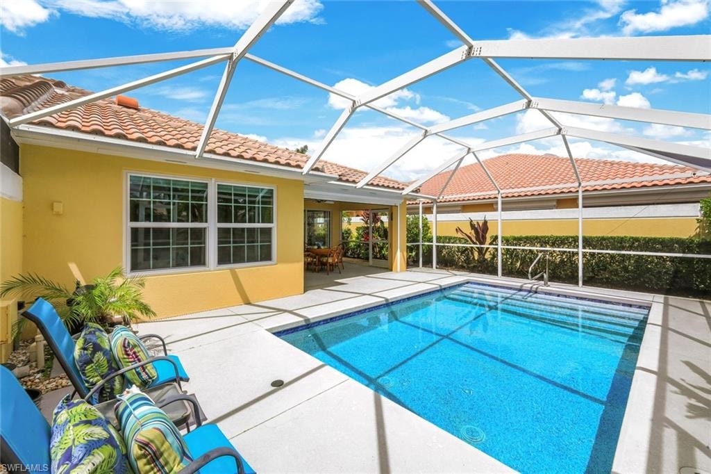 Screened-in pool deck featuring a rectangular swimming pool with blue tile interior, a concrete patio, and a covered lanai