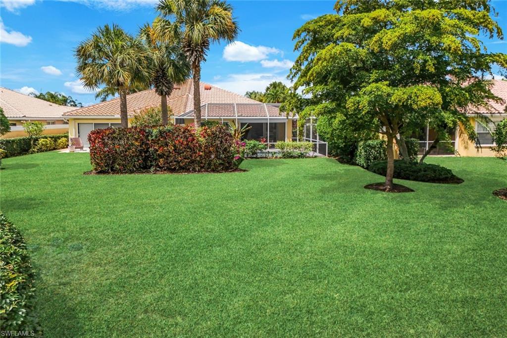 Expansive green lawn with mature trees and tropical landscaping