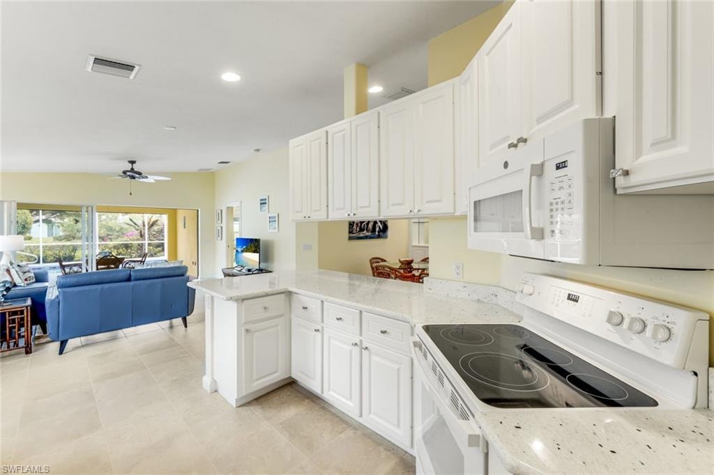Kitchen featuring white cabinetry, light-colored speckled countertops, and a built-in microwave
