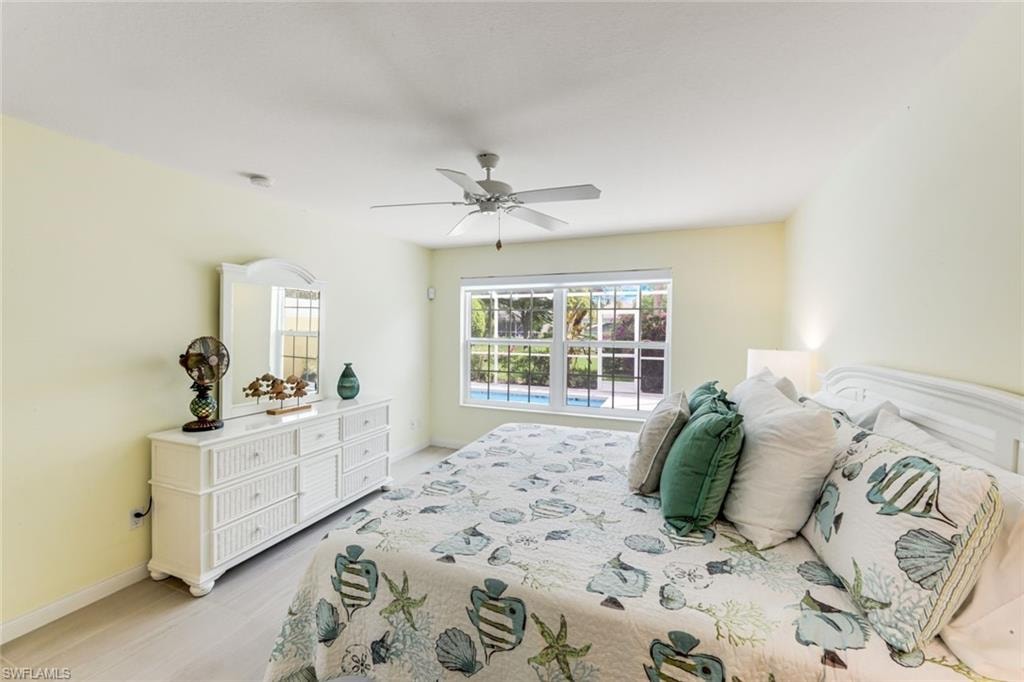 Spacious bedroom featuring light-toned walls, a ceiling fan, and light wood-finish flooring