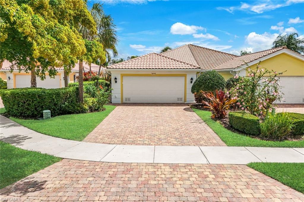 Exterior featuring a two-car garage, concrete tile roof, and a paver driveway