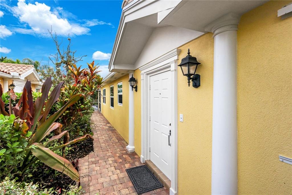 Front entry with a white paneled door, flanked by decorative columns and a wall-mounted lantern light fixture