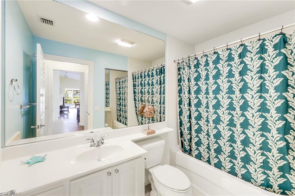 Bathroom featuring a white vanity with integrated sink, chrome faucet, and a wall-mounted mirror