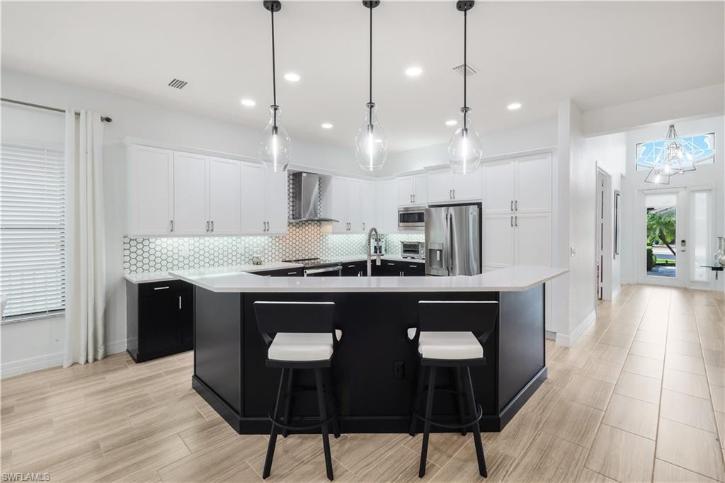 Renovated kitchen with quartz counter tops, wood cabinetry, stainless steel appliances, custom pendant lighting and tile floors.