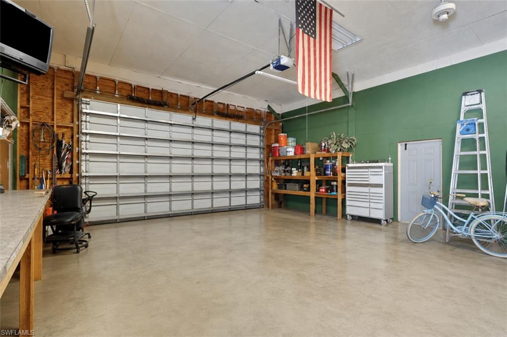 Spacious garage featuring a large sectional door, concrete flooring, recessed lighting, and a dedicated workspace with built-in shelving
