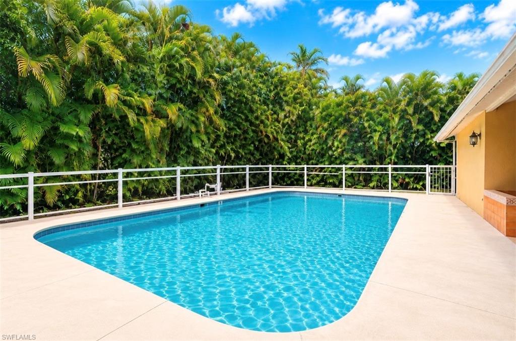 Outdoor swimming pool with a white perimeter fence and surrounding concrete decking