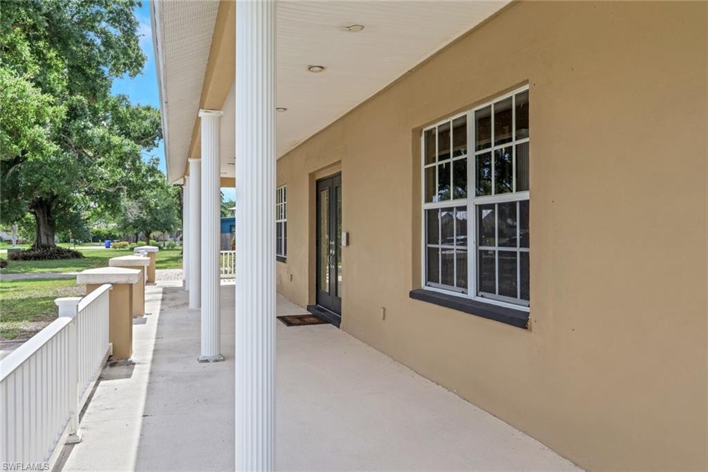 Exterior facade featuring a covered porch with white fluted columns, a concrete walkway, and a white railing system