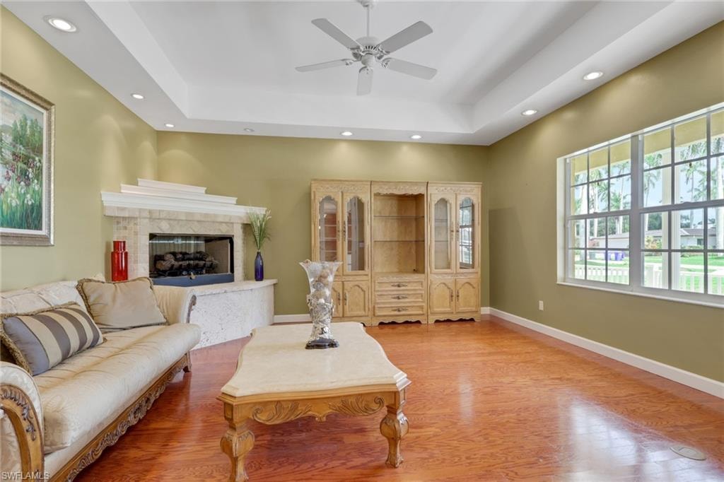 Living area featuring wood-finish flooring, a stone fireplace, recessed lighting, and a ceiling fan