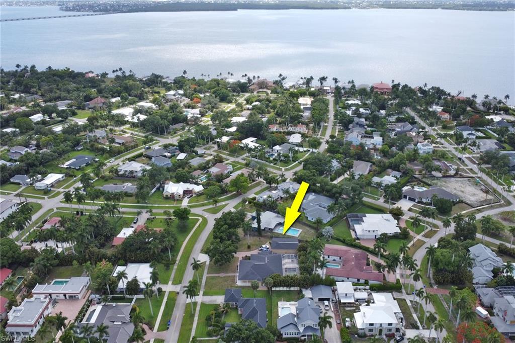Aerial perspective showcasing a residential neighborhood with surrounding water and a distant bridge