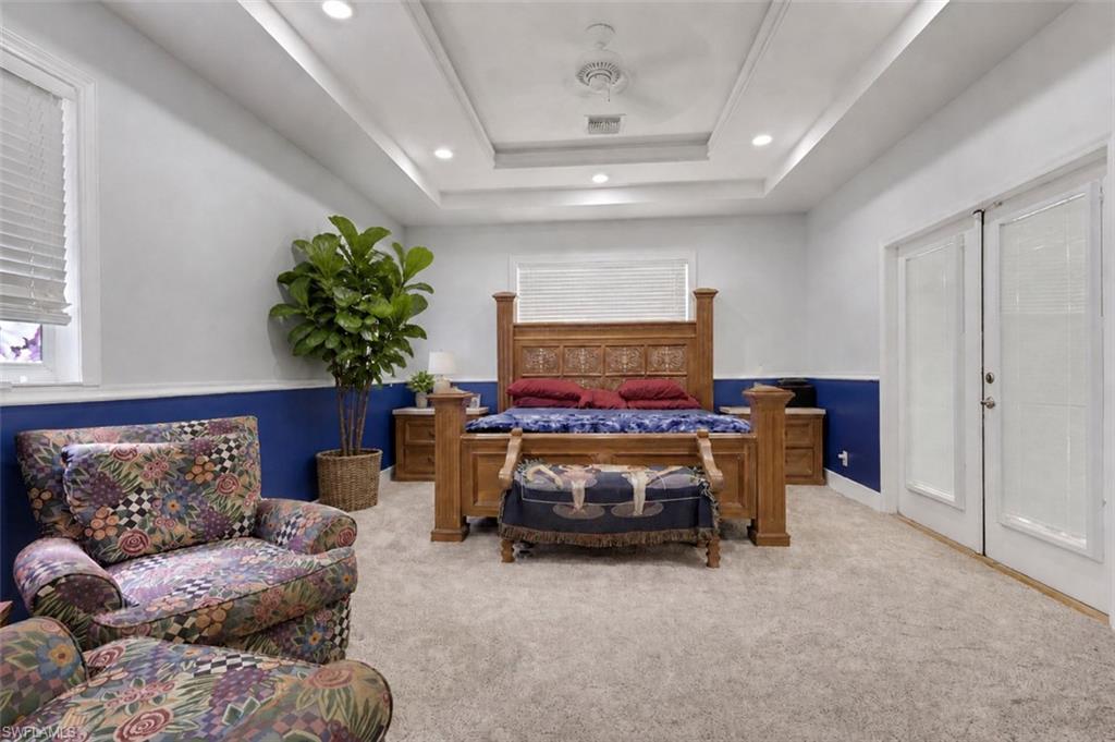 Expansive room featuring a tray ceiling with recessed lighting, carpet flooring, and two sets of window blinds