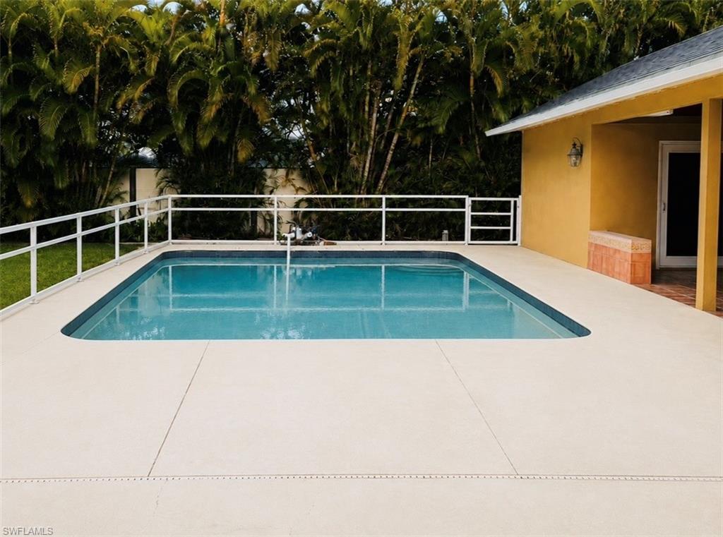 Rectangular swimming pool with light blue water and surrounding concrete patio