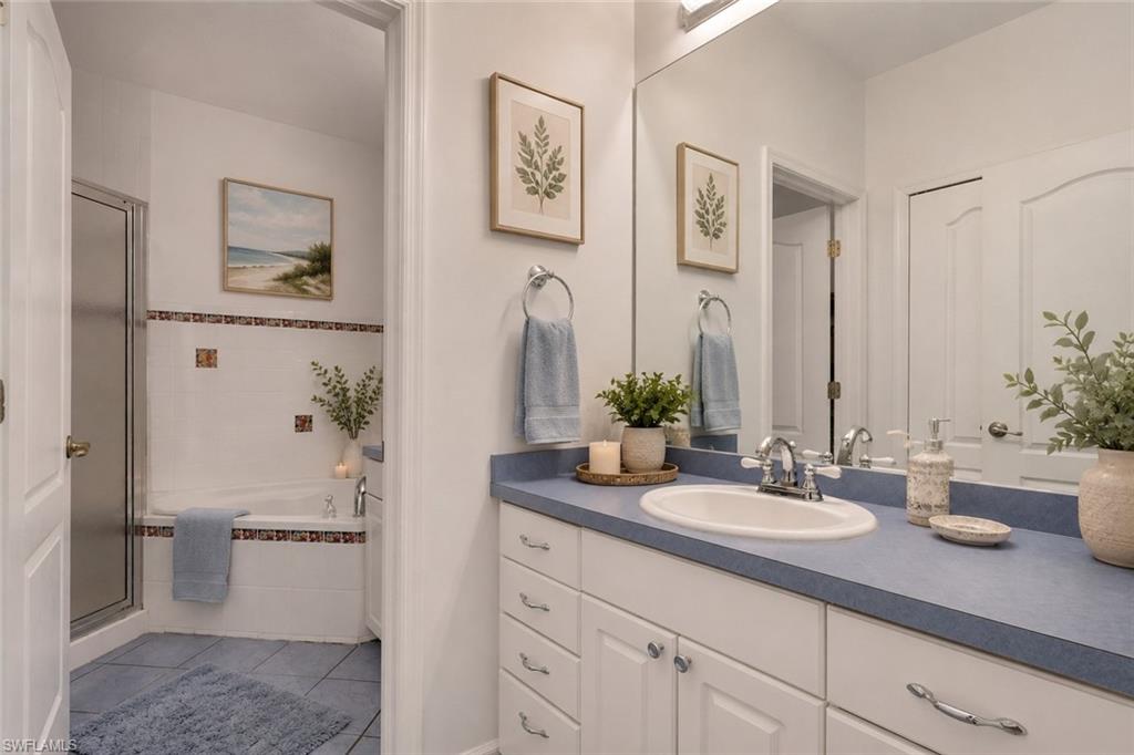 Bathroom vanity featuring a single basin sink set into a blue countertop, white cabinetry with silver hardware, and a large wall-mounted mirror