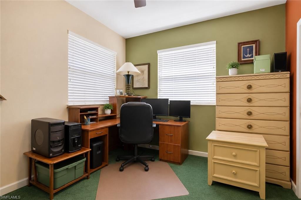 Dedicated office space featuring two windows with horizontal blinds, a corner desk, and green wall accents