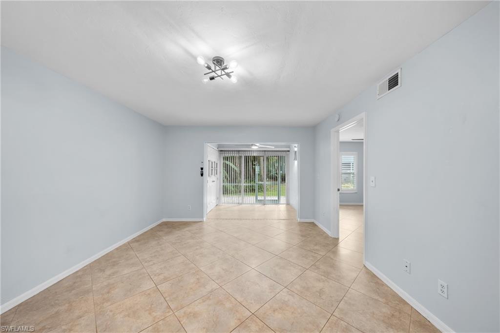 Spacious interior room featuring light-colored tile flooring, neutral wall paint, and a modern ceiling light fixture