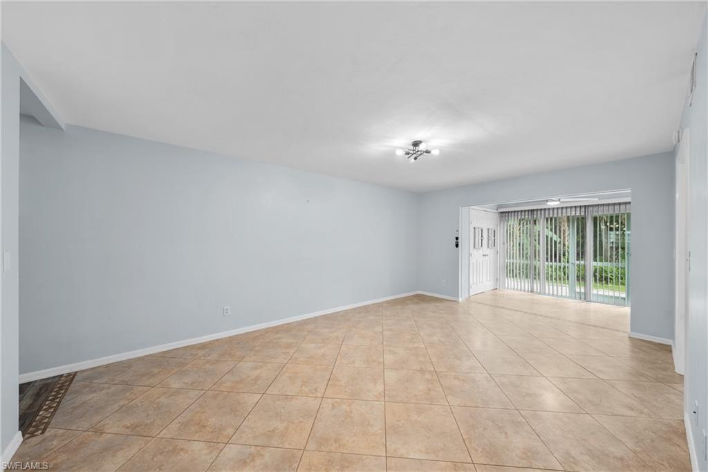 Spacious room featuring neutral tile flooring, light blue walls, and a white ceiling with a flush-mount light fixture