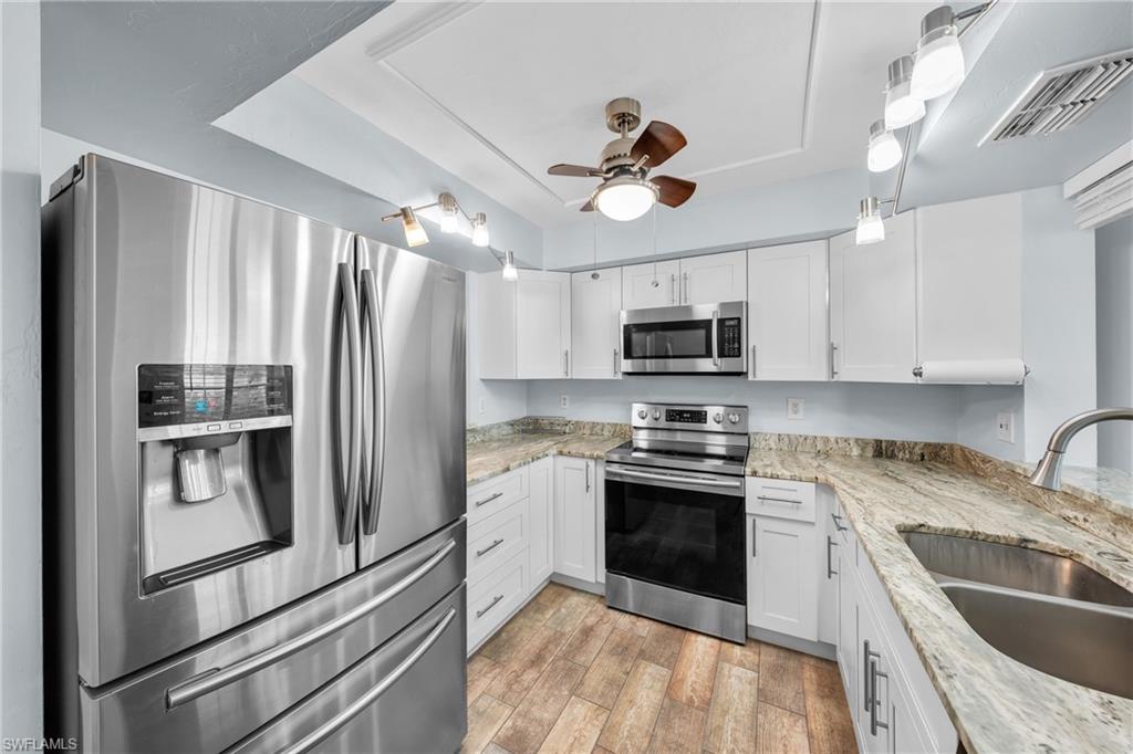 Well-appointed kitchen featuring stainless steel appliances, white cabinetry, and stone countertops