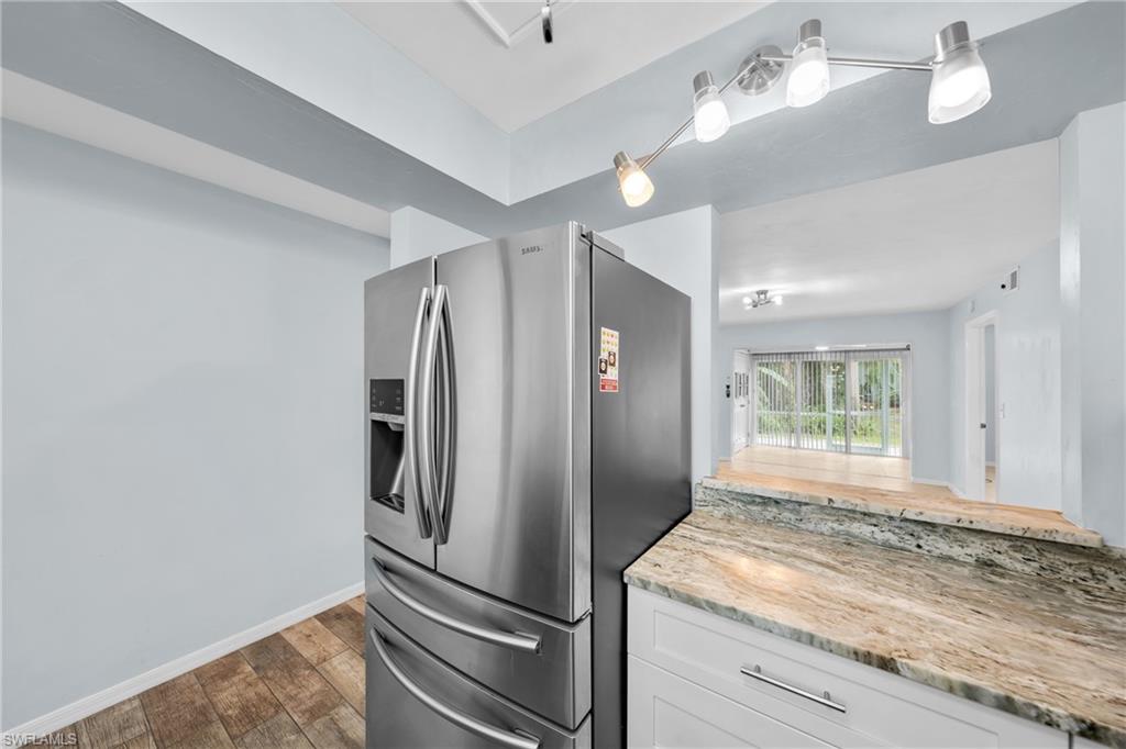 Stainless steel French door refrigerator with an ice and water dispenser, complemented by a stone countertop and white cabinetry