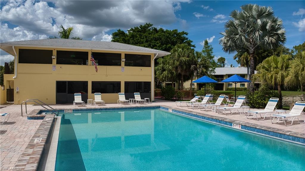 Resort-style swimming pool featuring a brick paver deck, surrounding lounge areas, and tropical landscaping