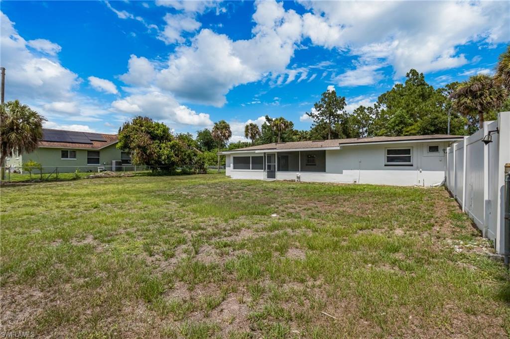 Expansive rear yard featuring a privacy fence, mature palm trees, and established landscaping