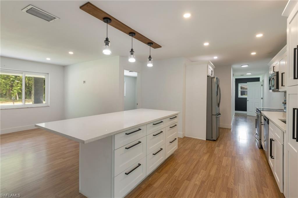 Bright kitchen featuring an expansive central island with a white countertop and abundant drawer storage