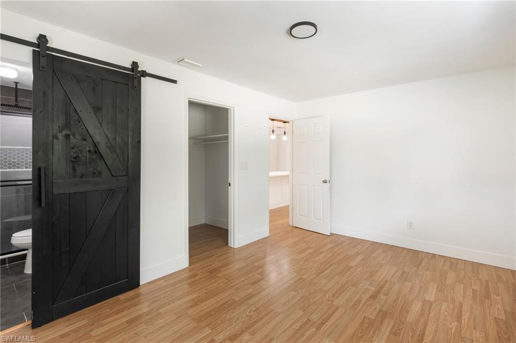Spacious room featuring wood-finish flooring, a contemporary black ceiling light, and a stylish black barn door