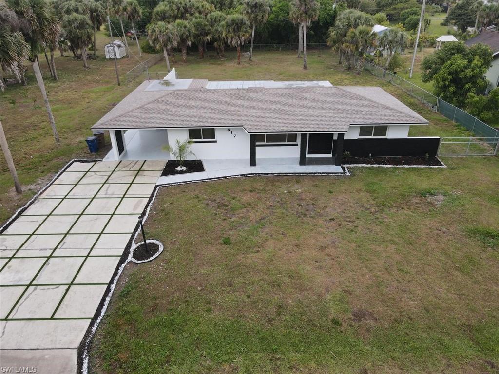 Ranch-style exterior featuring a gray shingle roof, white and black facade, and a concrete driveway