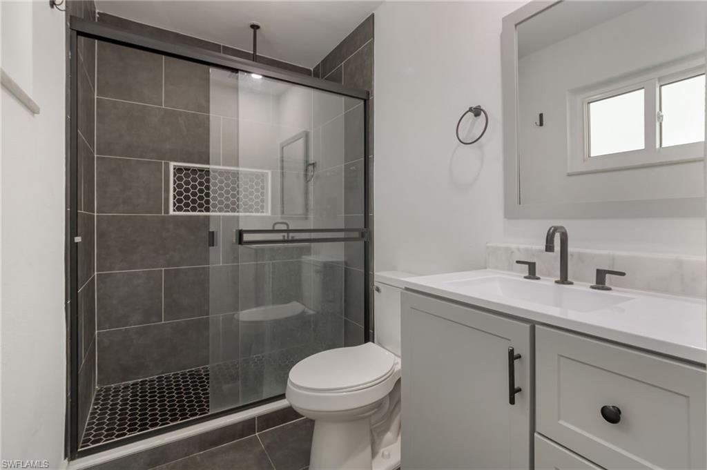 Modern bathroom featuring a glass-enclosed shower with dark tile walls and a hexagonal tile floor