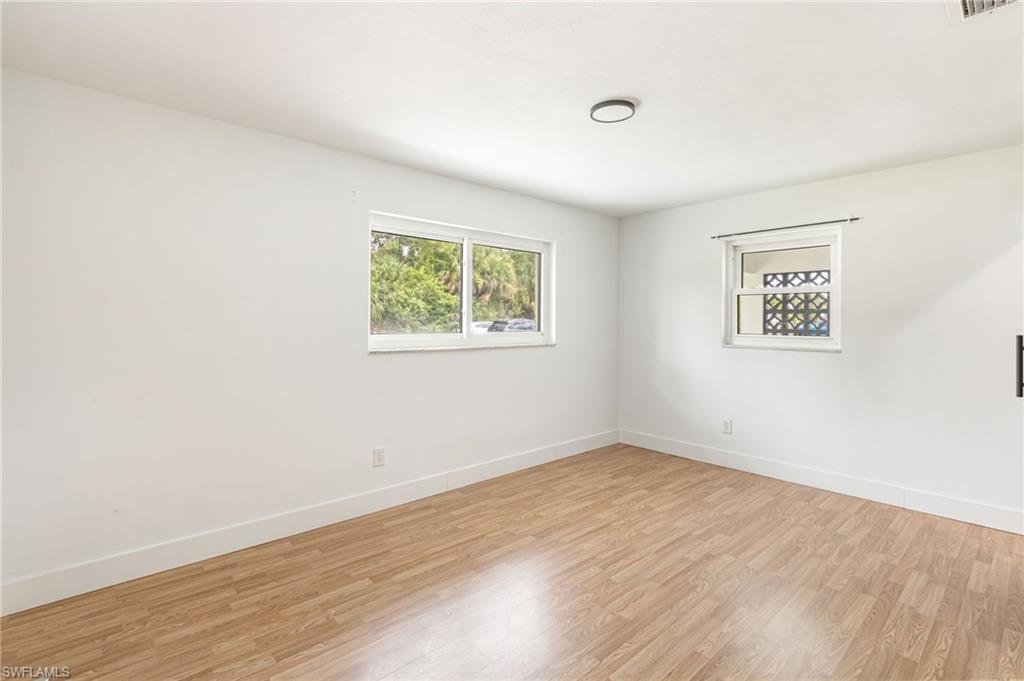 Neutral interior with wood-finish flooring, white walls, and bright white baseboards