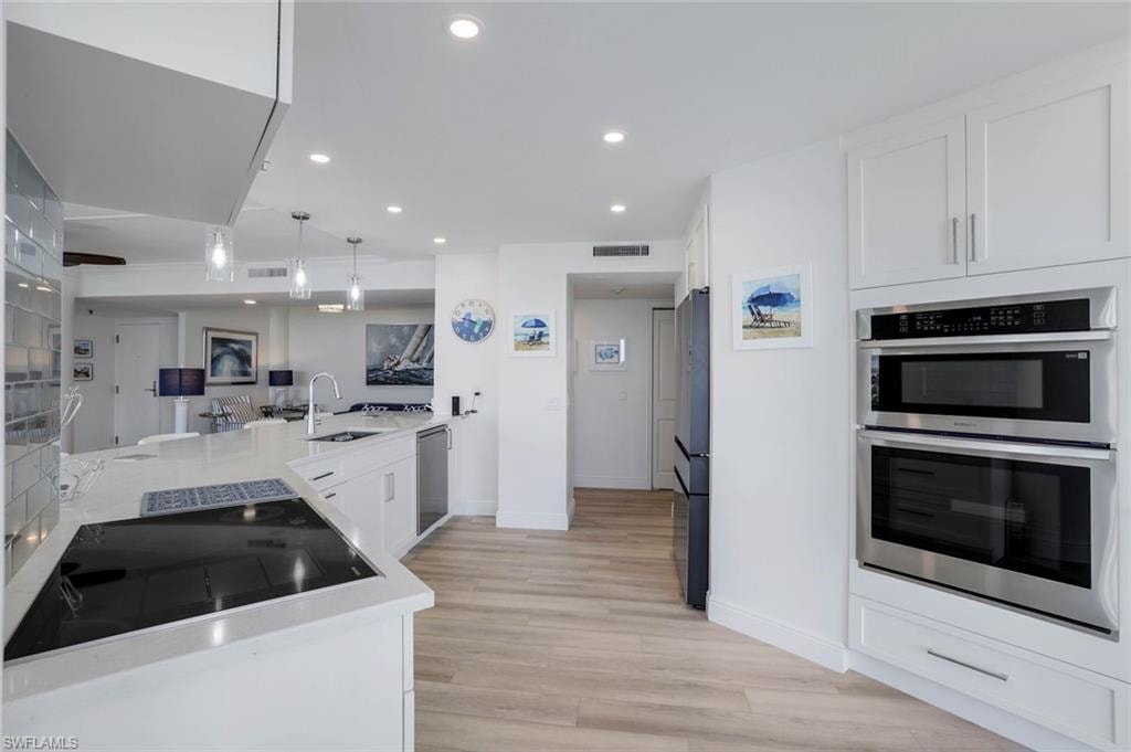 Kitchen featuring stainless steel appliances, a sink, white cabinets, baseboards, and light countertops