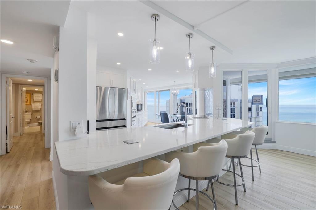 Kitchen featuring stainless steel fridge, a sink, light wood-type flooring, white cabinetry, and recessed lighting
