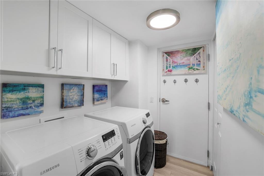Washroom with washing machine and clothes dryer, cabinet space, and light wood-style flooring