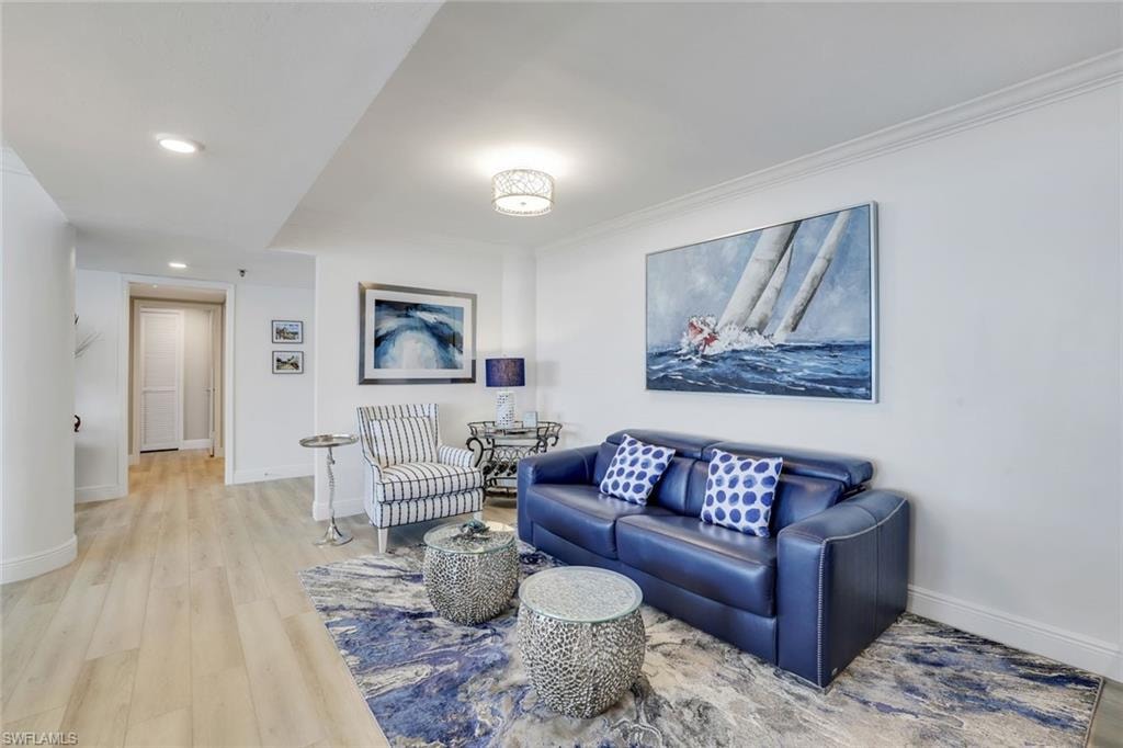 Living area with light wood finished floors, baseboards, recessed lighting, and crown molding