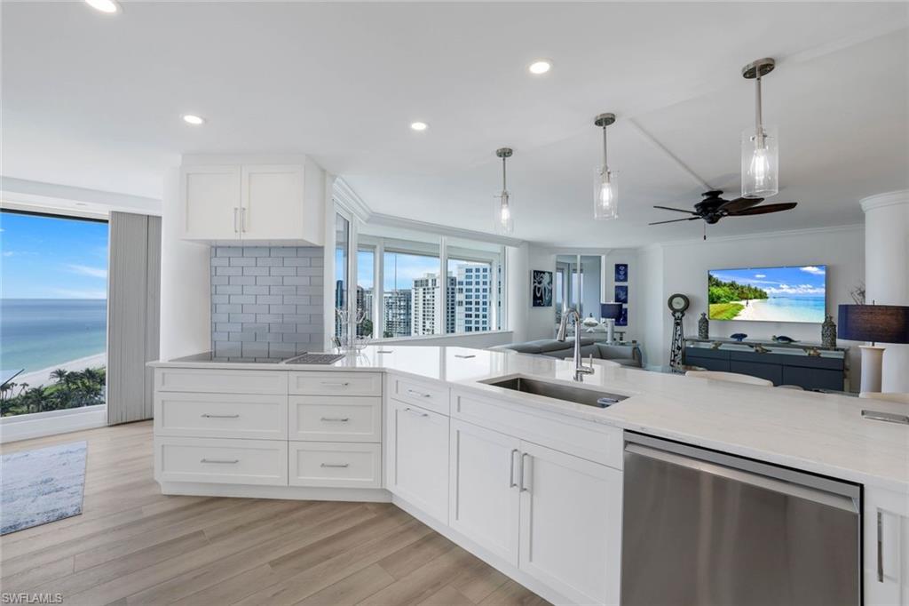 Kitchen with stainless steel dishwasher, a sink, open floor plan, recessed lighting, and hanging light fixtures