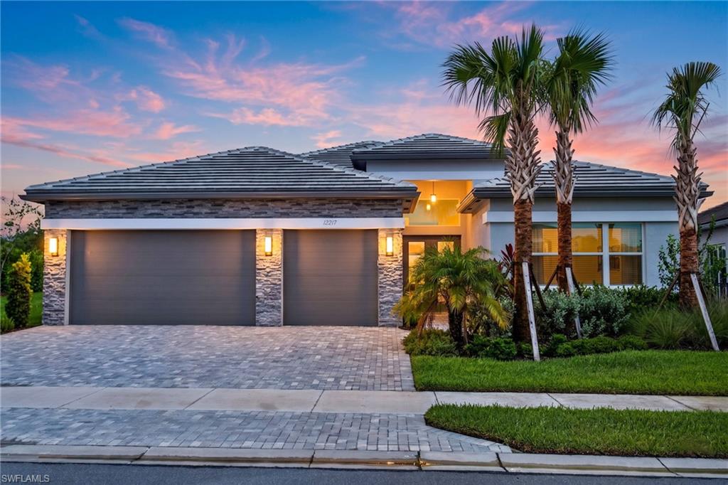 Contemporary facade featuring a stone veneer accent, paver driveway, and a tile roof
