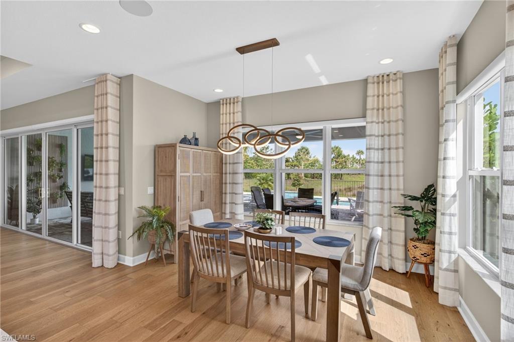 Dining area featuring wood-finish flooring, a contemporary chandelier, recessed ceiling lighting, and large windows with outdoor views