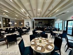 Spacious dining area featuring a coffered ceiling, multiple dining tables with dark upholstered seating, and recessed lighting