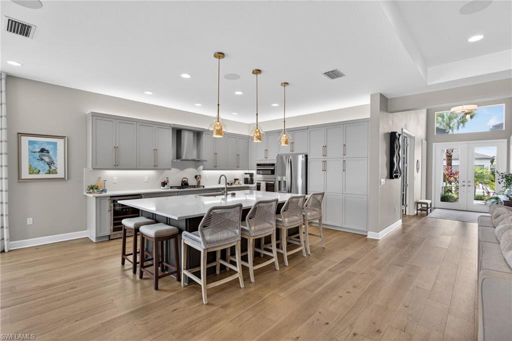 Spacious kitchen featuring a large central island with seating, light gray cabinetry, and stainless steel appliances