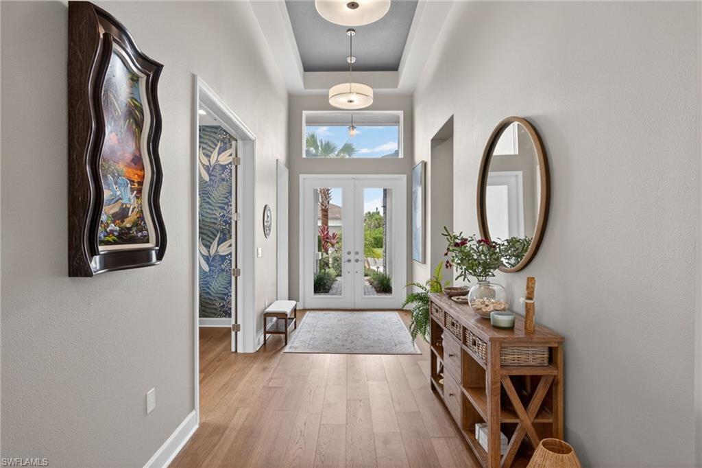Foyer featuring double entry doors, transom windows, wood-finish flooring, and a tray ceiling with recessed lighting