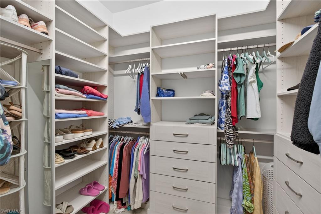 Custom closet system featuring extensive shelving, multiple hanging rods, built-in drawers with modern hardware, and dedicated shoe storage