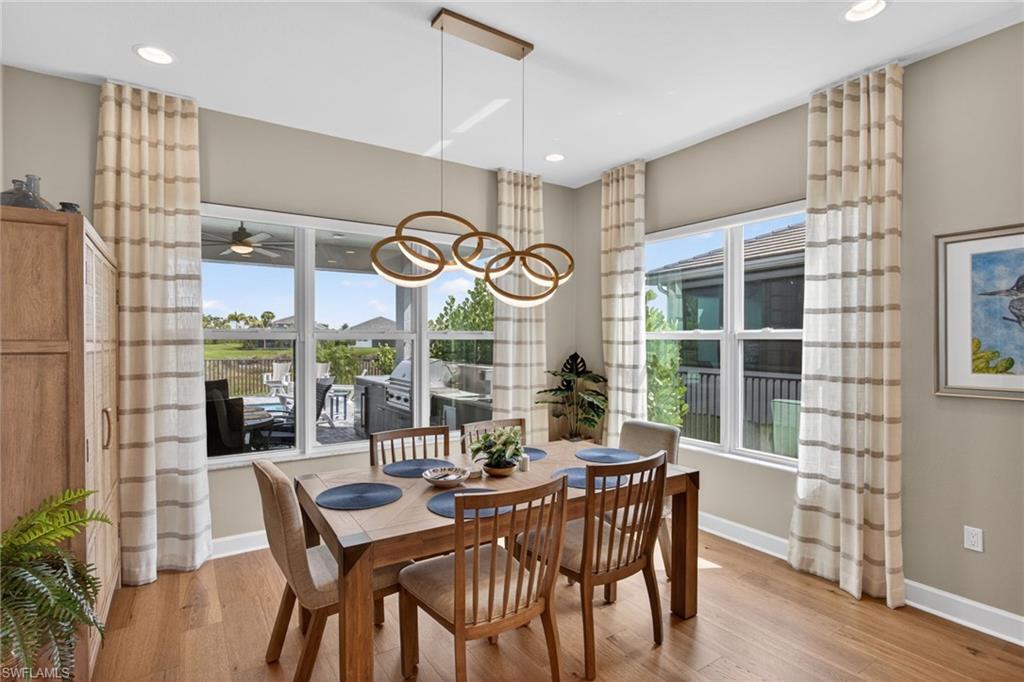 Dining area featuring wood-finish flooring, a modern chandelier with circular lighting, and recessed ceiling lights