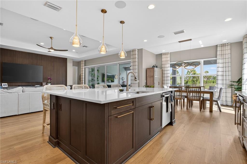 Spacious kitchen island with white countertop, dark wood-finish cabinetry, and gold-tone hardware