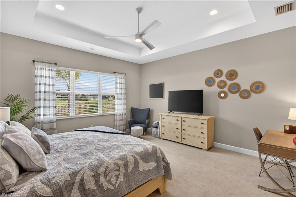 Spacious room featuring a tray ceiling with recessed lighting and a ceiling fan