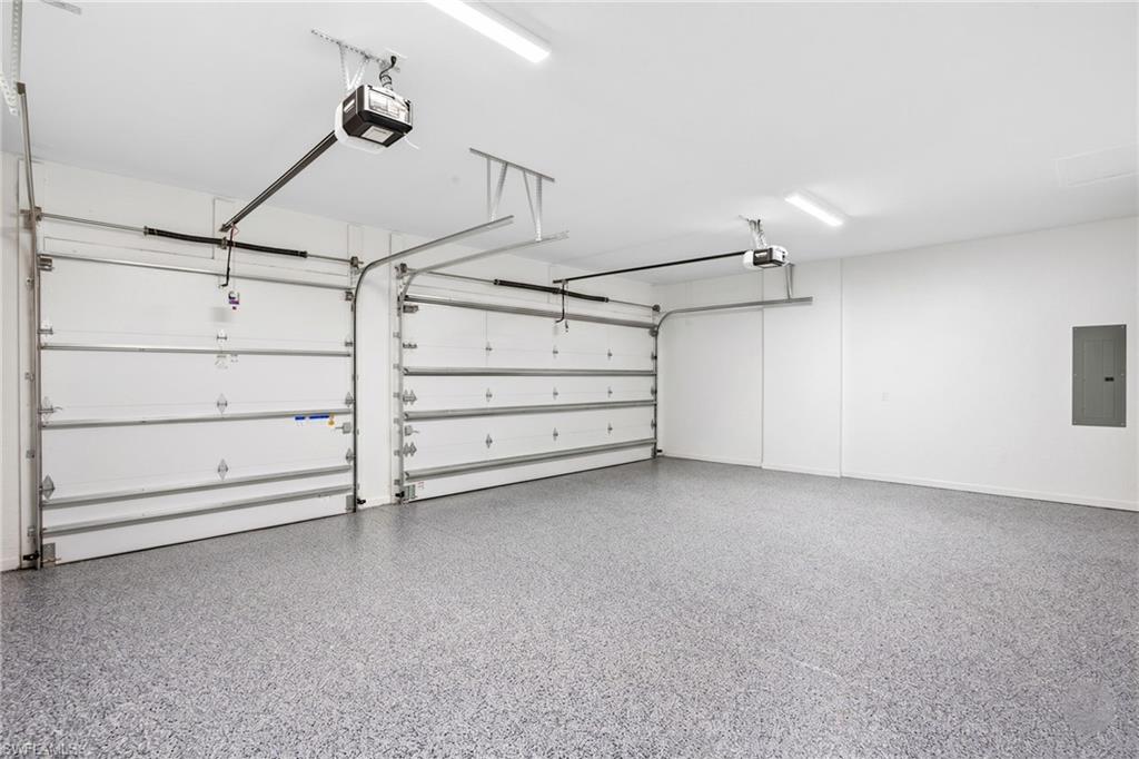 Spacious garage featuring two overhead doors with automatic openers, a speckled epoxy floor finish, and ample overhead lighting