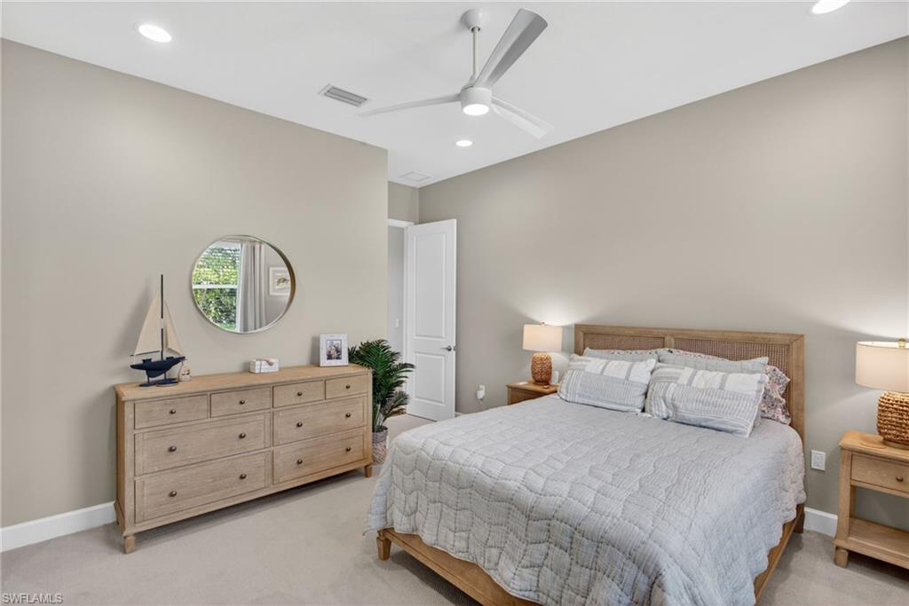 Neutral-toned bedroom featuring recessed lighting, a ceiling fan, light-colored carpeting, a window, and a white interior door