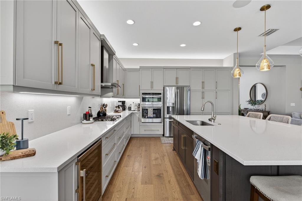 Contemporary kitchen featuring light gray cabinetry, stainless steel appliances, and wood-finish flooring