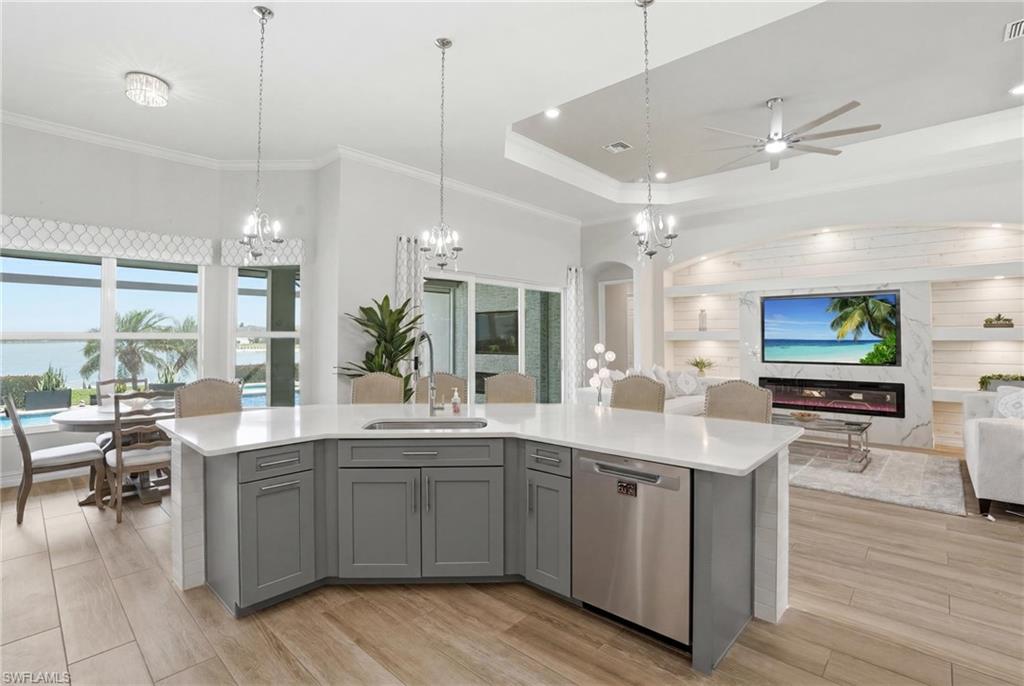 Contemporary kitchen island with grey cabinetry, white countertops, and stainless steel dishwasher