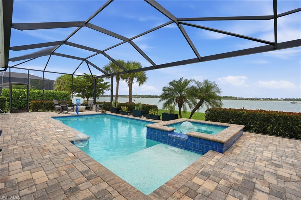 Screened lanai featuring a swimming pool, integrated spa with waterfall, and paver decking