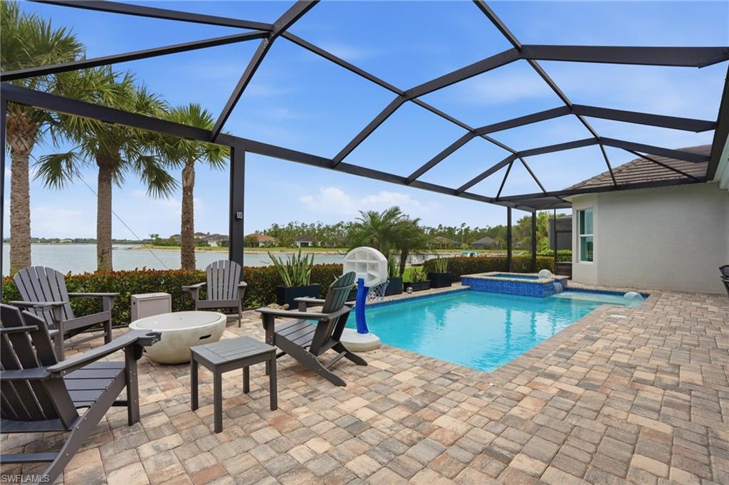 Screened outdoor living area featuring a rectangular pool and integrated spa