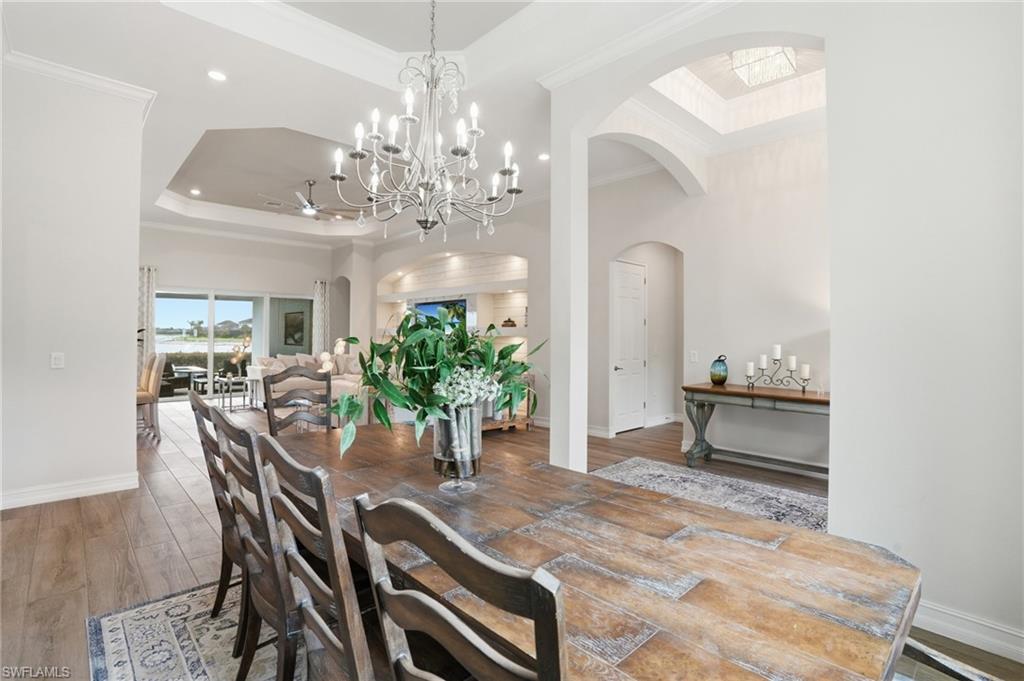 Spacious interior featuring wood-finish flooring, a tray ceiling, and an ornate chandelier
